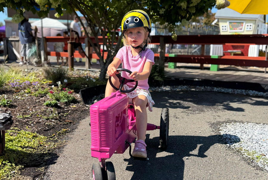 Our daughter riding a pink pedal tractor at the fair